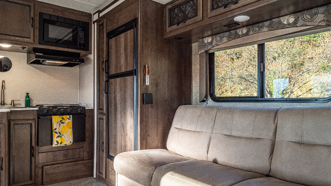 The interior of an RV with wood panelling and a couch.